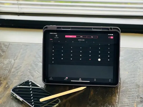 A tablet sitting on top of a table next to a pencil.