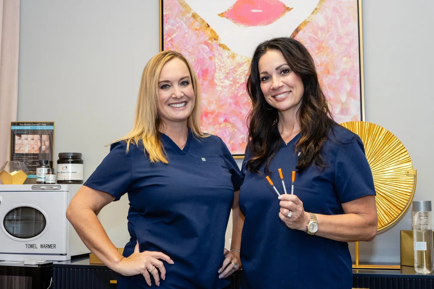 Two women in blue shirts holding toothbrushes