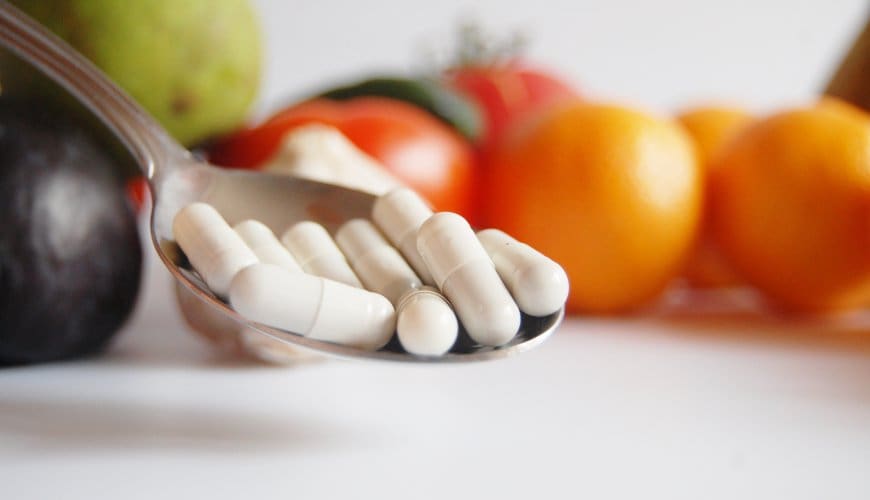 Spoonful of pills and fresh fruit.